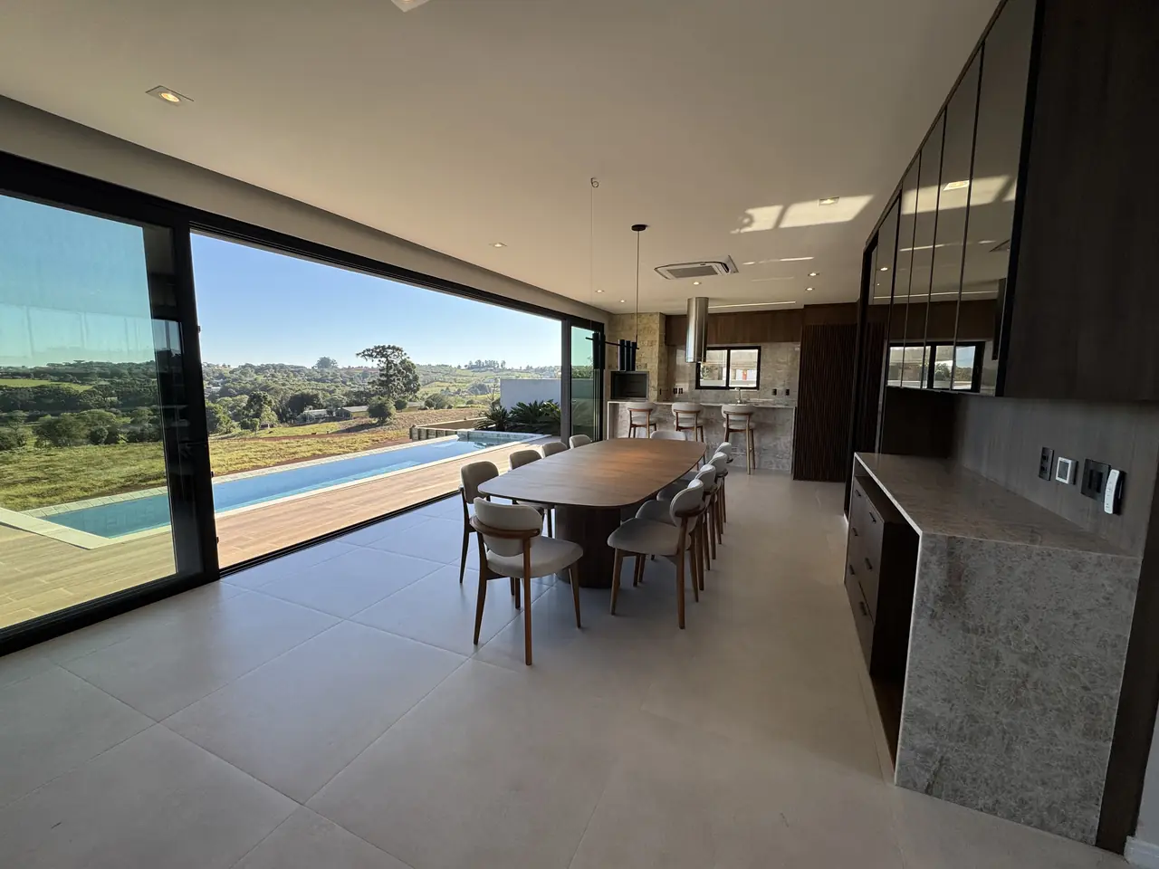 Sala de jantar da Casa Malbec aberta para a piscina e o campo