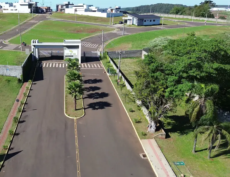 Portaria do Condomínio Luz do Sol vista de drone, com a avenida de entrada arborizada