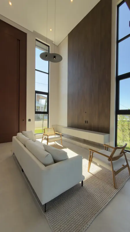 Sala com pé-direito duplo, painel de madeira e janelas do piso ao teto